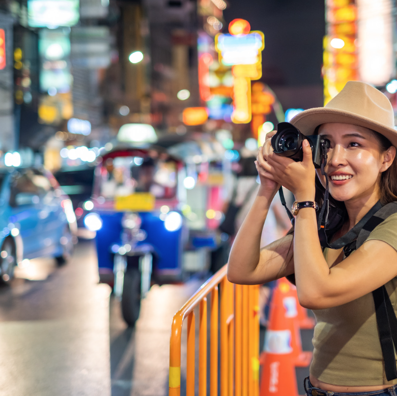 A visitor taking a photograph in a busy street